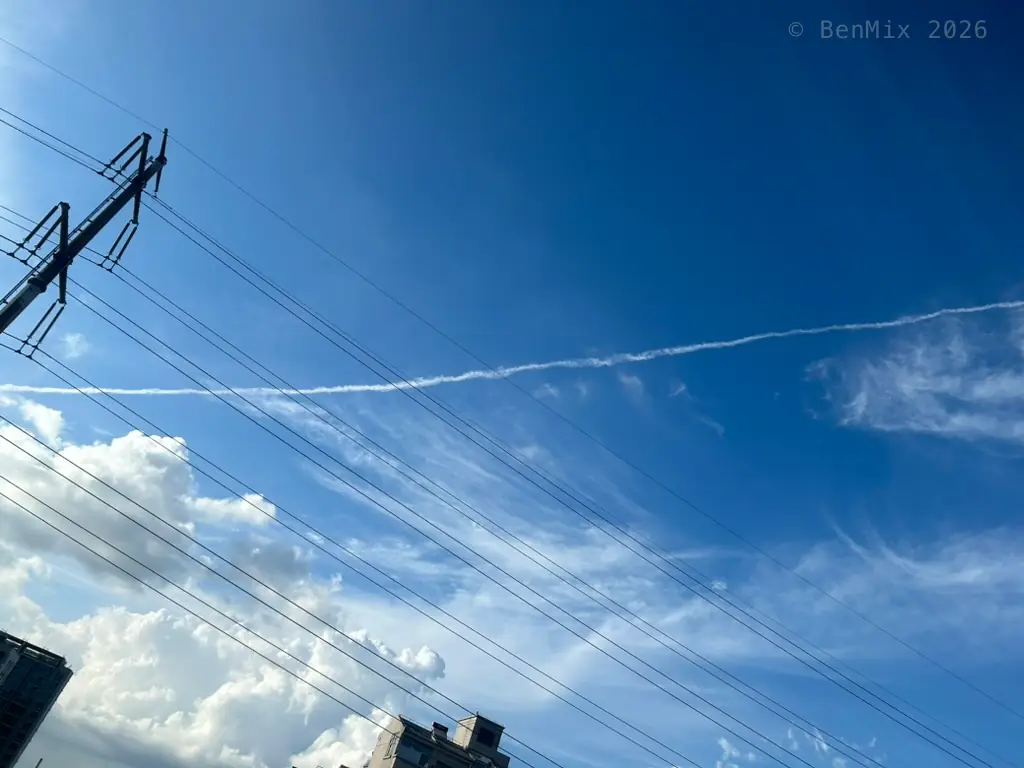 Summer sky over Minhang crossed by power lines and a contrail